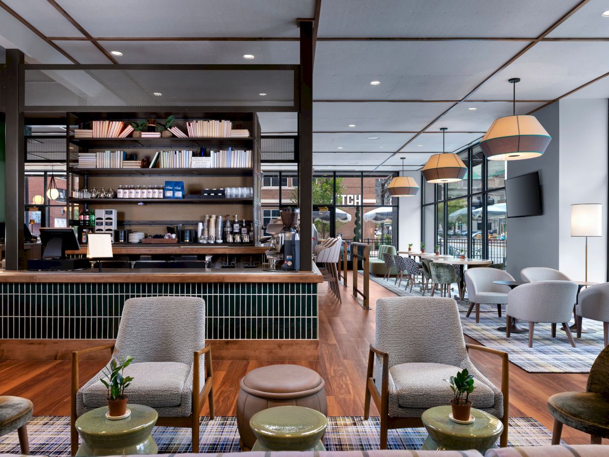 A modern café with a cozy seating area, stylish decor, bookshelves, and a well-lit bar counter, offering a welcoming ambiance to visitors.