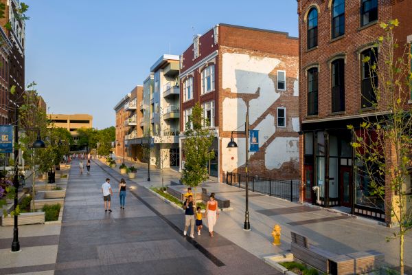 A pedestrian street showcases vibrant buildings and street lamps, with people leisurely walking and socializing along the pathway.