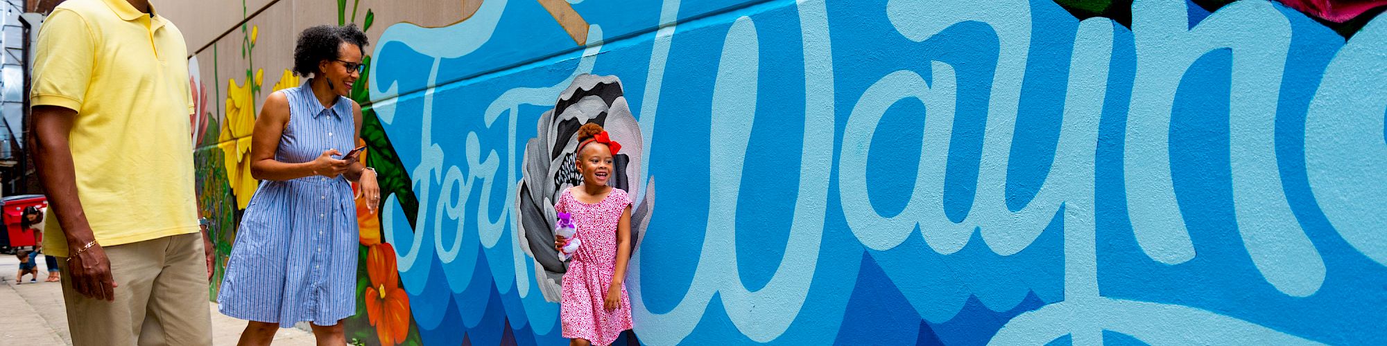 A family admires a colorful mural that says 