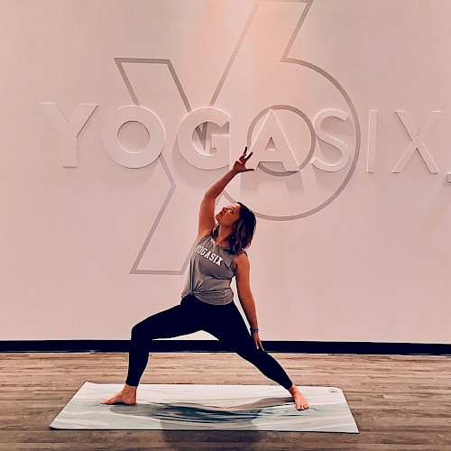 A person is performing a yoga pose on a mat in front of a 