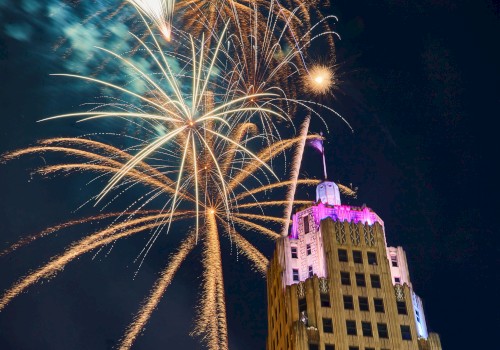 Fireworks burst in the night sky above a lit-up building.