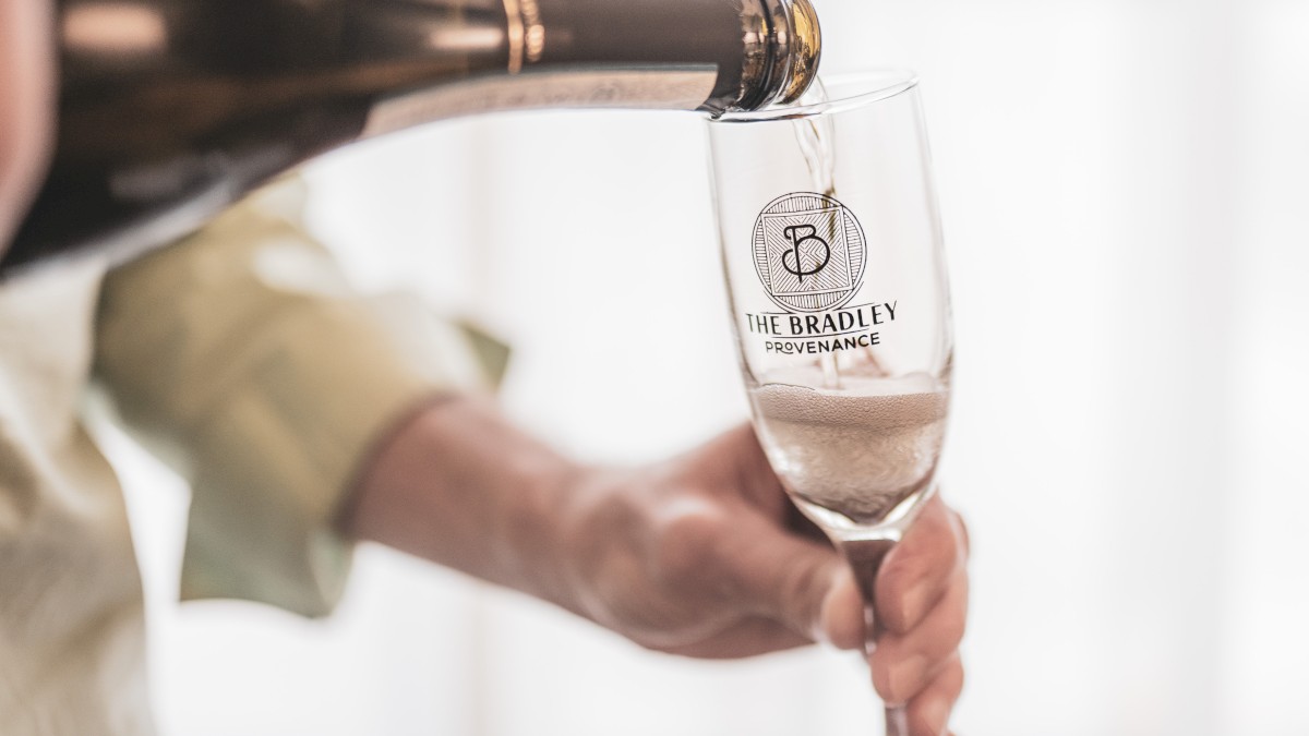 A person is pouring a beverage into a glass labeled 