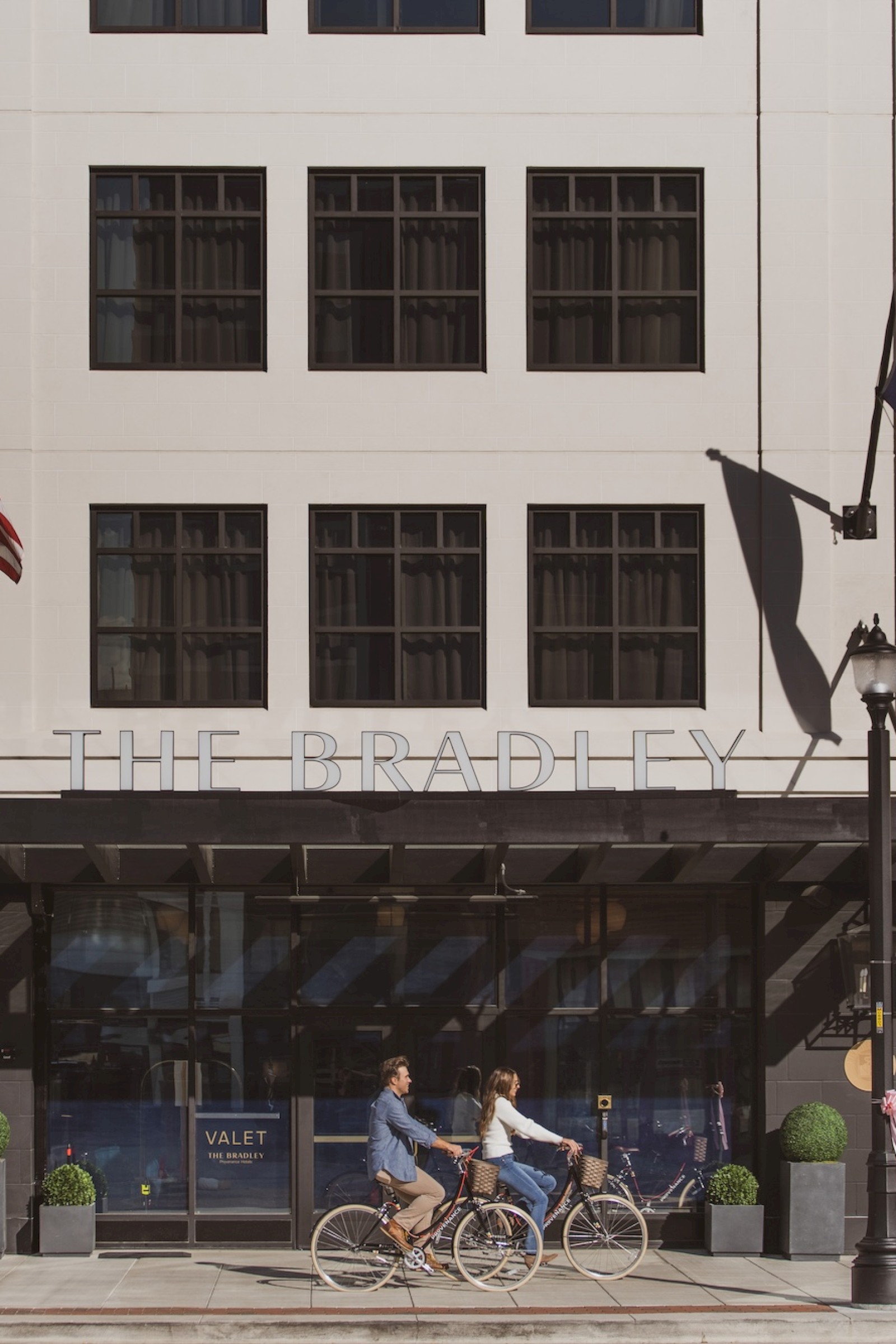 People ride bicycles past a building called 