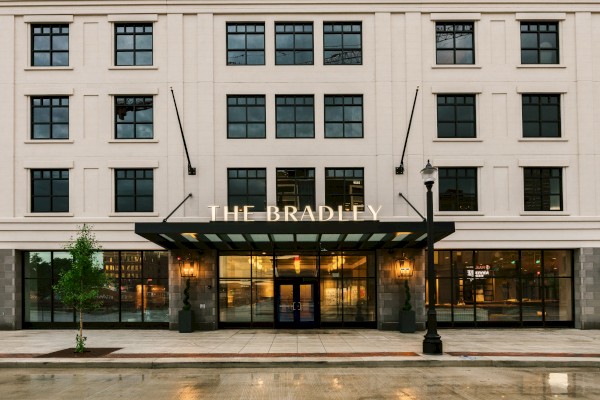 A four-story beige building with large windows and a glass awning labeled 